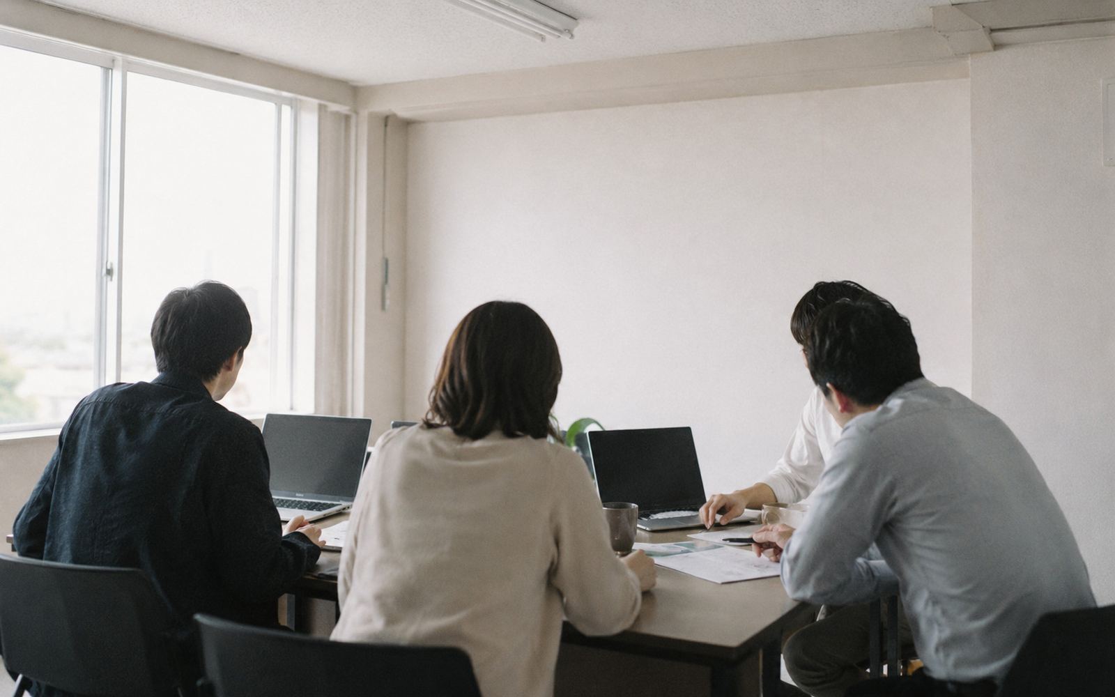 小規模なオフィスで、机を囲んで打ち合わせをしている様子
